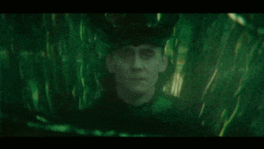 a close up of a man 's face in a dark room with a green background .