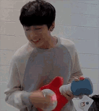 a young man is smiling while holding a stuffed animal and a toy gun .