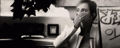 a black and white photo of a woman covering her mouth