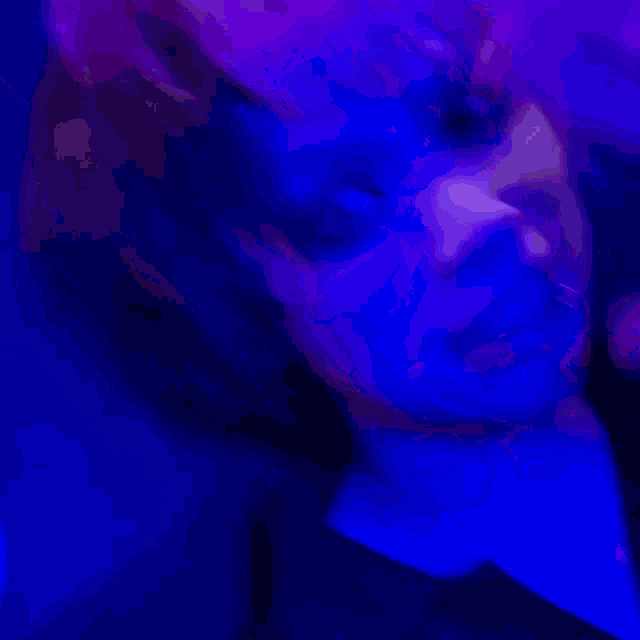 a close up of a person 's face with purple lights behind them