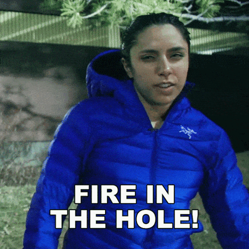 a woman in a blue jacket with the words fire in the hole below her