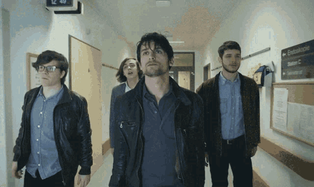 a group of men are walking down a hallway with a sign on the wall that says " zentrumsklinike "