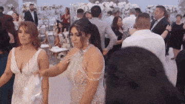 a woman in a silver dress is dancing with another woman