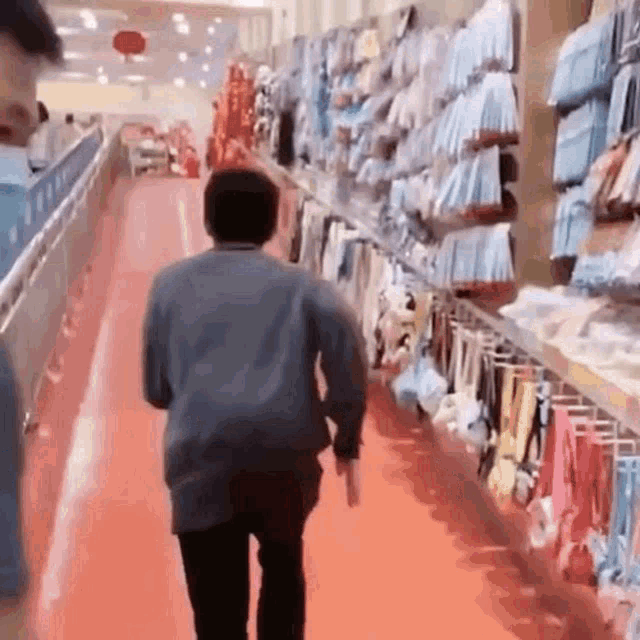 a man is walking down a red aisle of a store .