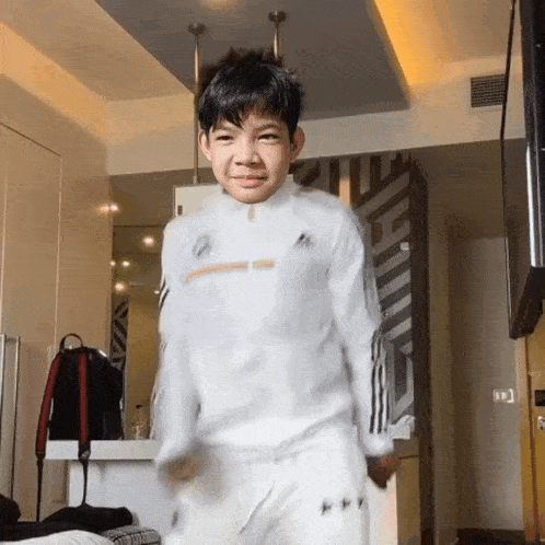 a young boy wearing a white adidas shirt is dancing