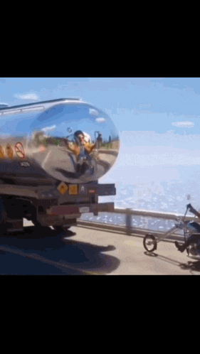 a tanker truck is pulling a motorcycle down the road
