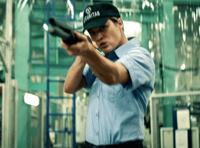 a man wearing a security hat holds a shotgun
