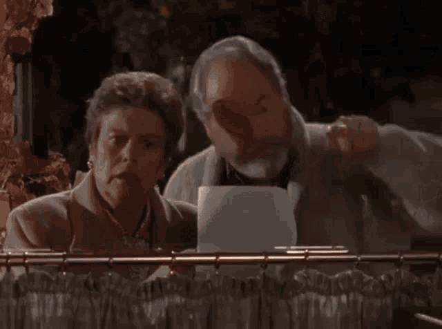 a man and a woman are looking through a window .