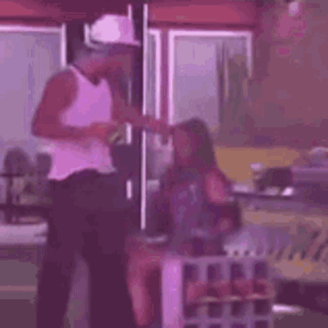 a man in a white tank top is standing next to a woman sitting on a crate .