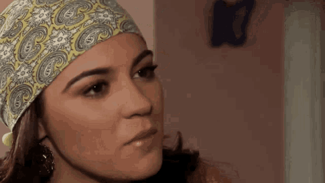 a close up of a woman wearing a headband and earrings .