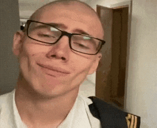a bald man wearing glasses is smiling and making a face .
