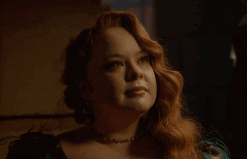 a woman with red hair and a pearl necklace