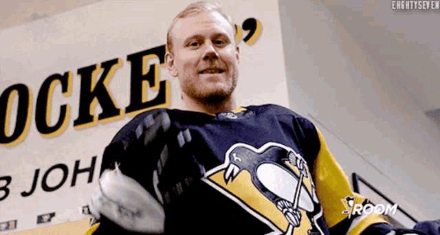 a man in a hockey jersey stands in front of a sign that says " ocke "