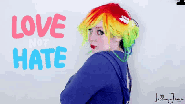 a woman with colorful hair is standing in front of a sign that says love not hate
