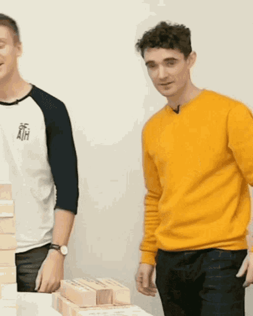 a man in a yellow sweater stands next to a man in a white shirt