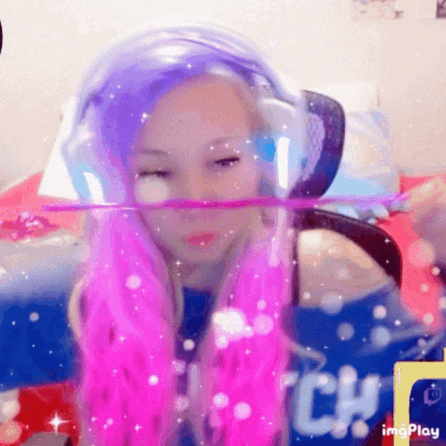 a girl with pink and purple hair is wearing headphones and a helmet on her head .