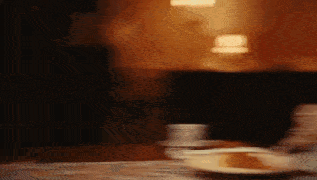 a person is sitting at a table with a plate of food and a cup of coffee on it .