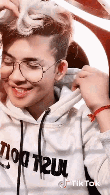a young man wearing glasses and a hoodie that says tik tok on it