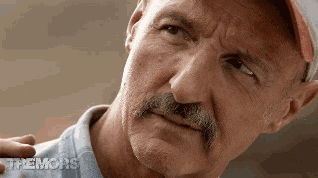 a close up of a man 's face with the words tremors on the bottom right