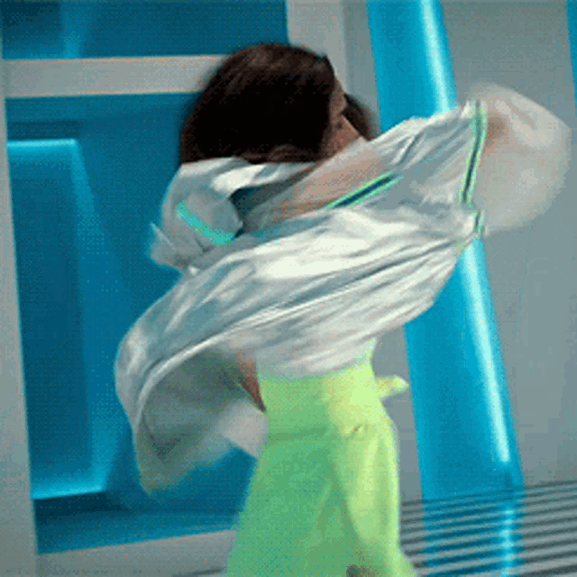 a woman in a white top and neon green pants is dancing