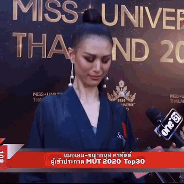 a woman stands in front of a sign that says miss universe