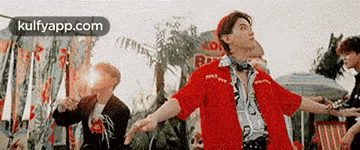 a man in a red shirt is dancing in front of a crowd of people .