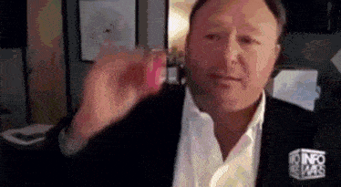 a man in a black jacket and white shirt is holding a red object in his hand .