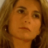 a close up of a woman 's face with a serious look on her face and earrings .