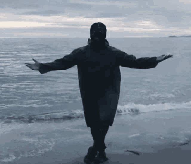 a person with their arms outstretched standing on the beach