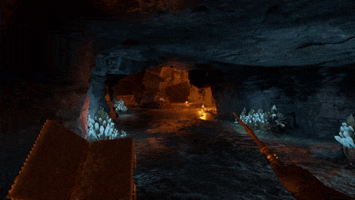 a person 's fist is being held up in a cave with a light coming out of it