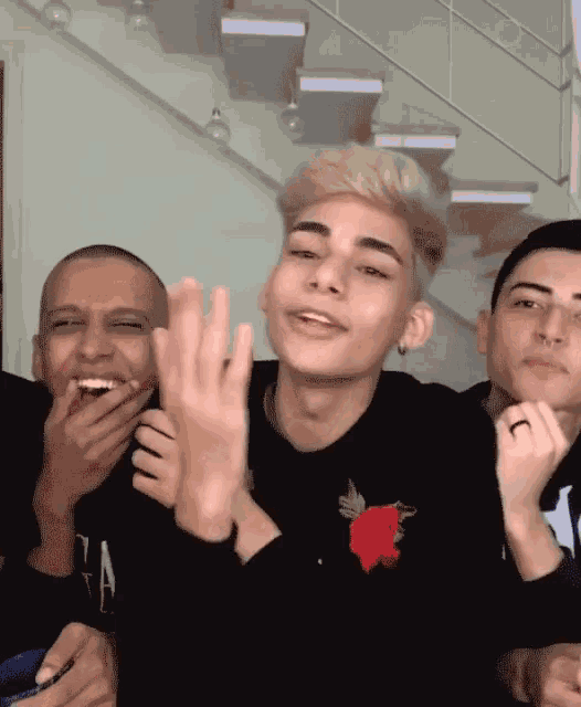 a group of young men are posing for a picture with one wearing a black shirt with a red rose on it