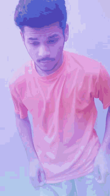 a young man in an orange shirt is standing in front of a white wall