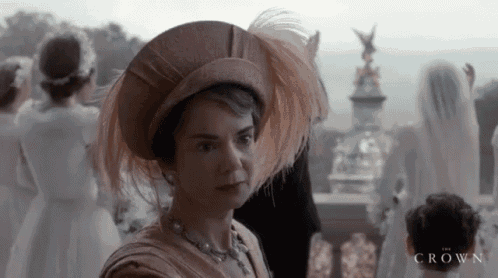 a woman wearing a feathered hat is standing in front of a group of people with the word crown on the bottom