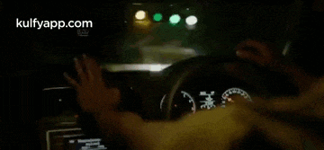 a man is driving a car at night and holding a cell phone in front of his face ..