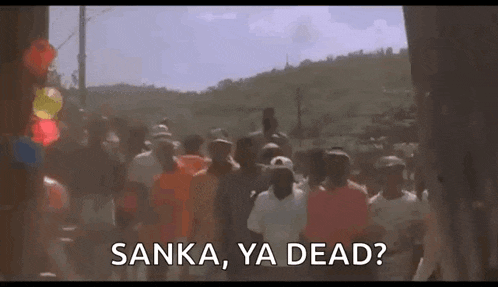 a group of people are walking down a street with the words `` kanka , ya dead '' written on the bottom .