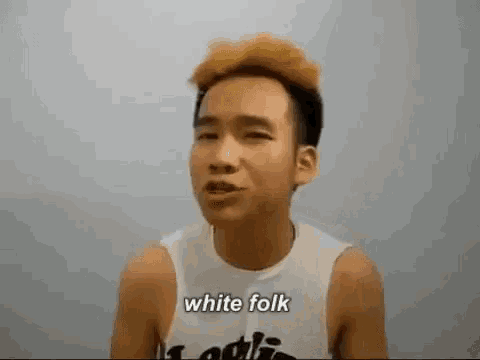 a man wearing a white tank top with the words `` white folk '' on it is making a funny face .