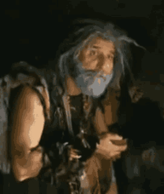 a man with a beard and long hair is holding a sword in his hand .