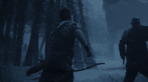 a man holding a bow and arrow stands next to another man holding an axe in a snowy forest