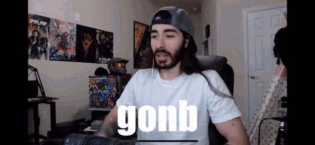 a man with long hair and a hat is sitting in front of a microphone with the word gonb on the screen