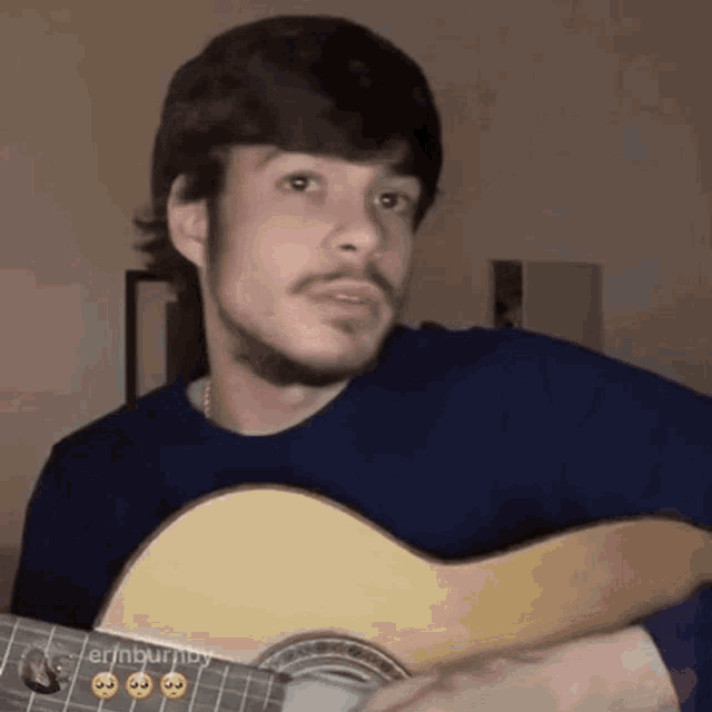 a man with a beard is playing a guitar in a room .