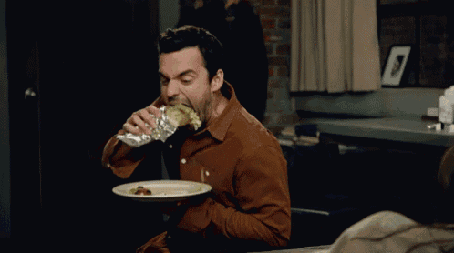 a man in a brown shirt is eating a piece of food