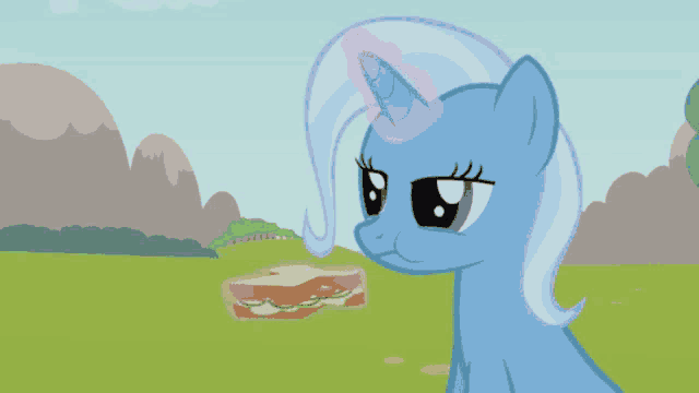 a blue pony with a pink horn looks at a sandwich in a field