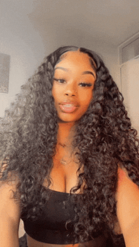 a woman with long curly hair wearing a black top