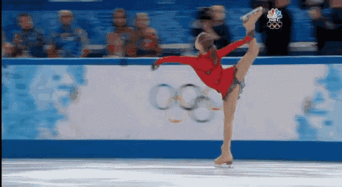 a female figure skater is doing a split in front of a nbc sign