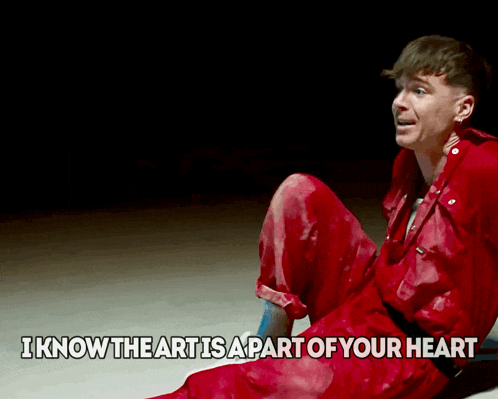 a man in a red jumpsuit sits on the ground with the words " i know the art is a part of your heart "