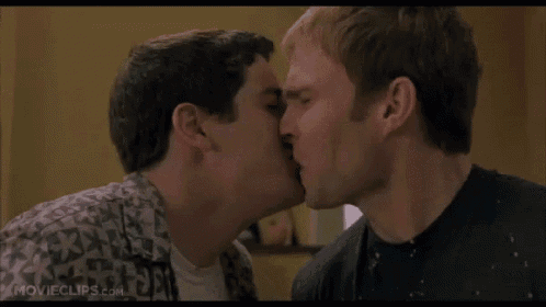 two men are kissing each other in front of a window .