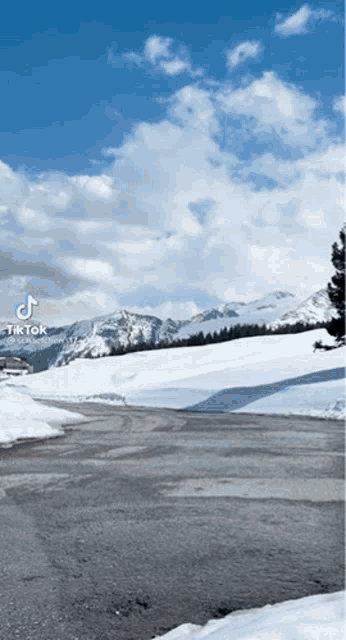 a snowy road with mountains in the background and a tik tok logo on the bottom