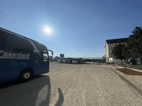 a blue tourist bus is parked in a parking lot