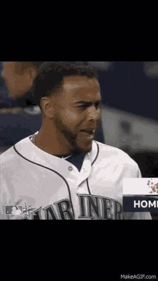 a baseball player with a beard is wearing a white jersey with the word mariner on it