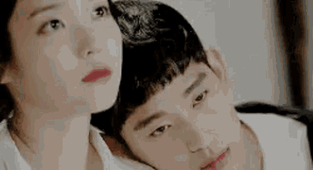 a man and a woman are looking at each other . the woman is laying on the man 's chest .